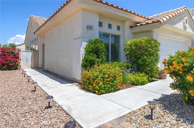 8312 Raphael Ct, Las Vegas, NV 89129 - view of property exterior with a tiled roof, a garage, and stucco siding