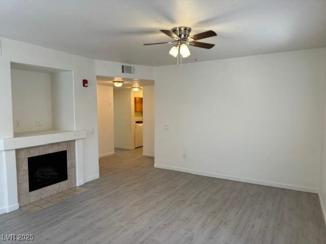 10290 Gilmore Canyon Ct Unit 103, Las Vegas, NV 89129 - unfurnished living room featuring a ceiling fan, wood finished floors, a tiled fireplace, and baseboards