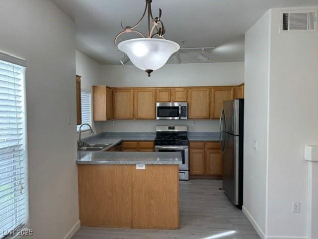 10290 Gilmore Canyon Ct Unit 103, Las Vegas, NV 89129 - kitchen featuring stainless steel appliances, a sink, a peninsula, light wood-type flooring, and baseboards
