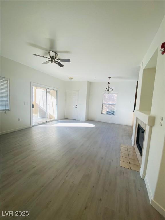 10290 Gilmore Canyon Ct Unit 103, Las Vegas, NV 89129 - unfurnished living room with wood finished floors, plenty of natural light, a tile fireplace, and a ceiling fan