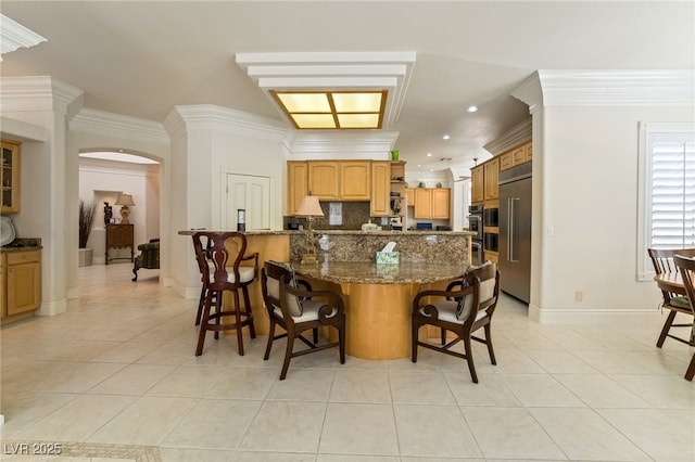 277 Dark Forest Ave, Las Vegas, NV 89123 - kitchen with high end refrigerator, light tile patterned floors, arched walkways, a breakfast bar area, and decorative backsplash