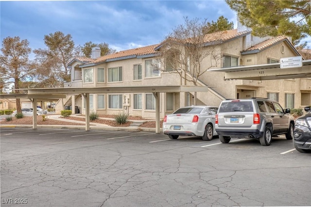 5265 Caspian Springs Dr Unit 201, Las Vegas, NV 89120 - view of front of house with stairway, covered parking, a tile roof, a chimney, and stucco siding