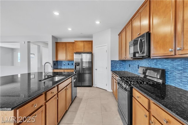 2832 Aragon Terrace Way, Henderson, NV 89044 - kitchen featuring appliances with stainless steel finishes, a sink, brown cabinetry, light tile patterned floors, and dark stone counters