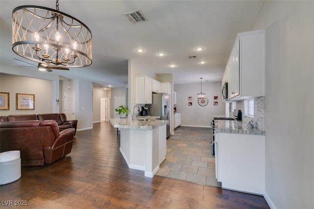 2111 Tiger Links Dr, Henderson, NV 89012 - kitchen featuring stainless steel appliances, open floor plan, white cabinets, baseboards, and recessed lighting