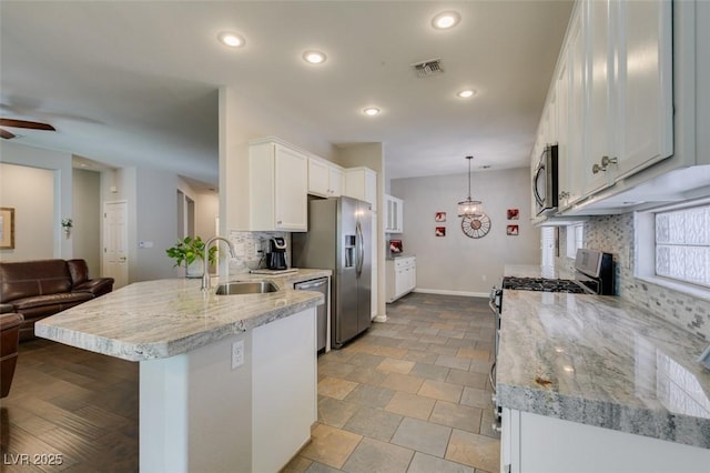2111 Tiger Links Dr, Henderson, NV 89012 - kitchen featuring a sink, appliances with stainless steel finishes, tasteful backsplash, a peninsula, and white cabinetry