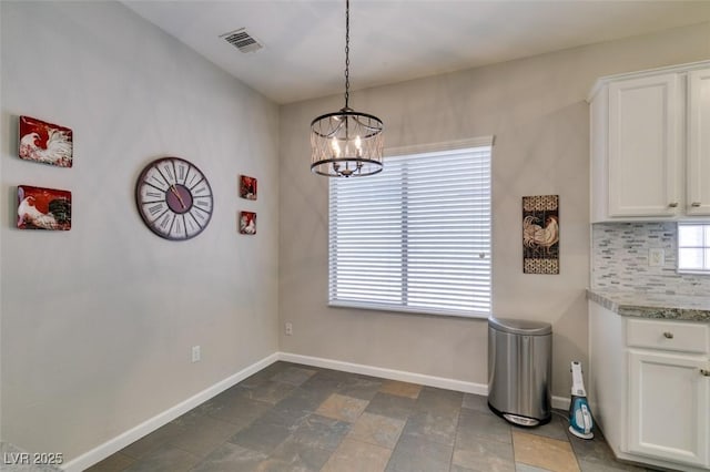 2111 Tiger Links Dr, Henderson, NV 89012 - unfurnished dining area featuring baseboards, a chandelier, and stone finish floors