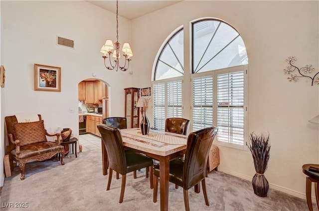 3987 Saddlewood Ct, Las Vegas, NV 89121 - dining room featuring light colored carpet, plenty of natural light, arched walkways, a chandelier, and a towering ceiling