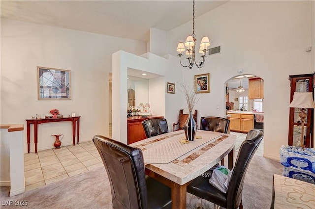 3987 Saddlewood Ct, Las Vegas, NV 89121 - dining room with a chandelier, light colored carpet, arched walkways, a high ceiling, and light tile patterned flooring