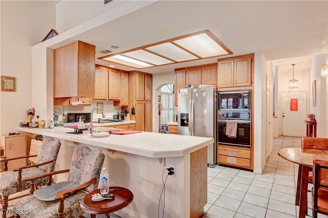 3987 Saddlewood Ct, Las Vegas, NV 89121 - kitchen featuring oven, stainless steel fridge, built in microwave, a peninsula, and tile countertops