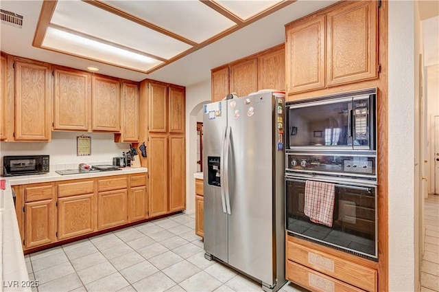 3987 Saddlewood Ct, Las Vegas, NV 89121 - kitchen with black appliances, tile counters, light tile patterned floors, and arched walkways