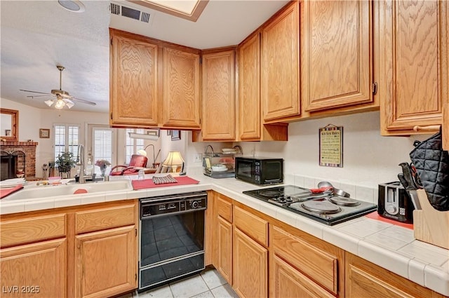 3987 Saddlewood Ct, Las Vegas, NV 89121 - kitchen with black appliances, light tile patterned flooring, a ceiling fan, a peninsula, and tile counters