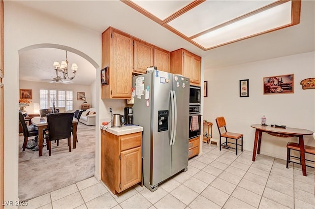 3987 Saddlewood Ct, Las Vegas, NV 89121 - kitchen featuring stainless steel fridge, black oven, arched walkways, light tile patterned floors, and light colored carpet