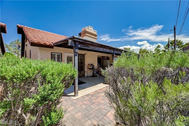 3987 Saddlewood Ct, Las Vegas, NV 89121 - back of house featuring a patio, a chimney, stucco siding, and a tile roof