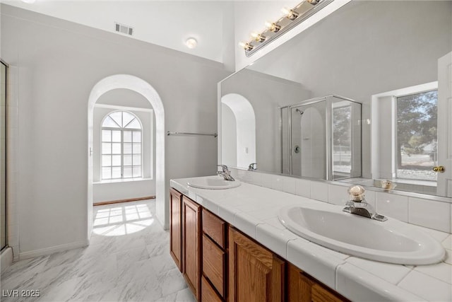 3580 S Shawnee Ave, Pahrump, NV 89048 - full bathroom featuring double vanity, a stall shower, a high ceiling, marble finish floors, and baseboards