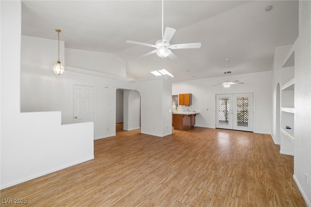 3580 S Shawnee Ave, Pahrump, NV 89048 - unfurnished living room featuring a ceiling fan, arched walkways, light wood finished floors, baseboards, and high vaulted ceiling