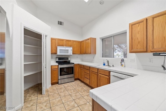 3580 S Shawnee Ave, Pahrump, NV 89048 - kitchen with white appliances, tile counters, a sink, light tile patterned floors, and high vaulted ceiling