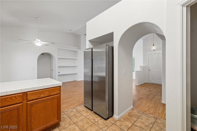 3580 S Shawnee Ave, Pahrump, NV 89048 - kitchen featuring freestanding refrigerator, arched walkways, vaulted ceiling, built in shelves, and tile counters