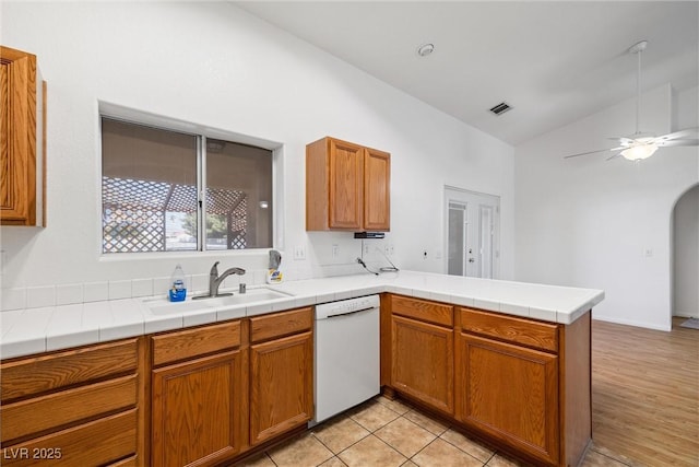 3580 S Shawnee Ave, Pahrump, NV 89048 - kitchen with white dishwasher, a sink, a peninsula, a ceiling fan, and brown cabinets