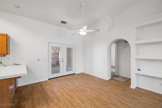 3580 S Shawnee Ave, Pahrump, NV 89048 - unfurnished living room with built in shelves, ceiling fan, light wood-style floors, and arched walkways