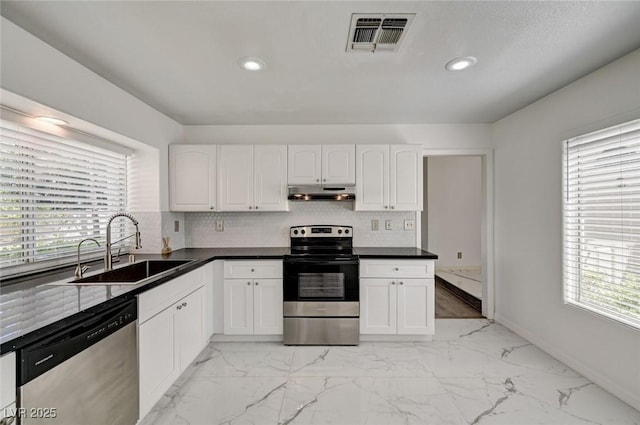 6944 Emerald Springs Ln, Las Vegas, NV 89113 - kitchen featuring stainless steel appliances, under cabinet range hood, white cabinets, light marble finish flooring, and recessed lighting