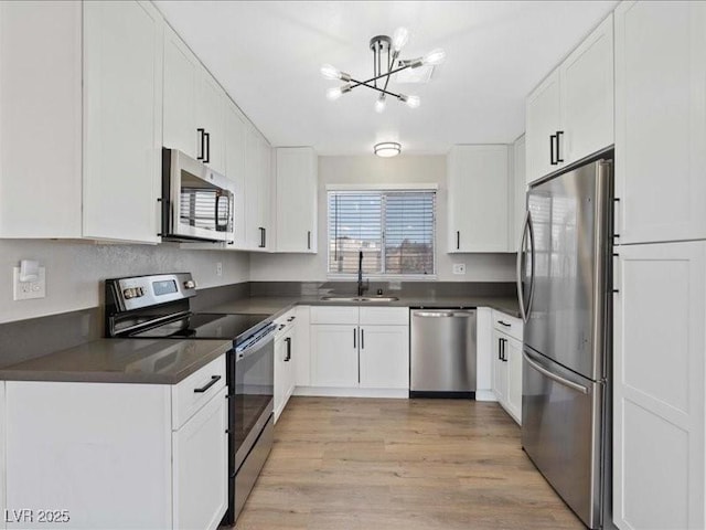 4204 El Jardin Ave, Las Vegas, NV 89102 - kitchen featuring stainless steel appliances, a sink, dark countertops, a chandelier, and light wood finished floors