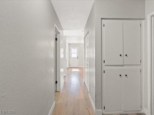 4204 El Jardin Ave, Las Vegas, NV 89102 - hallway featuring light wood finished floors, a textured wall, baseboards, and a textured ceiling