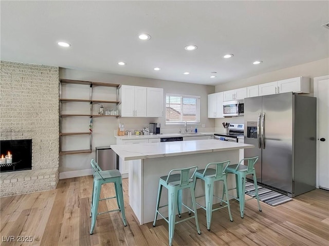 4072 E Harmon Ave, Las Vegas, NV 89121 - kitchen with stainless steel appliances, white cabinets, a kitchen breakfast bar, a sink, and recessed lighting