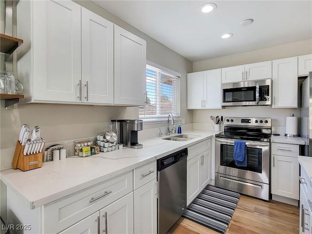 4072 E Harmon Ave, Las Vegas, NV 89121 - kitchen featuring stainless steel appliances, open shelves, a sink, white cabinetry, and light wood-type flooring
