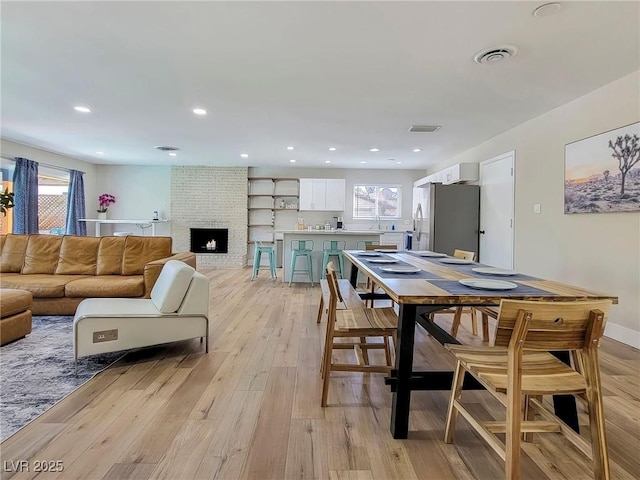 4072 E Harmon Ave, Las Vegas, NV 89121 - dining space featuring plenty of natural light, light wood-style floors, a brick fireplace, and recessed lighting
