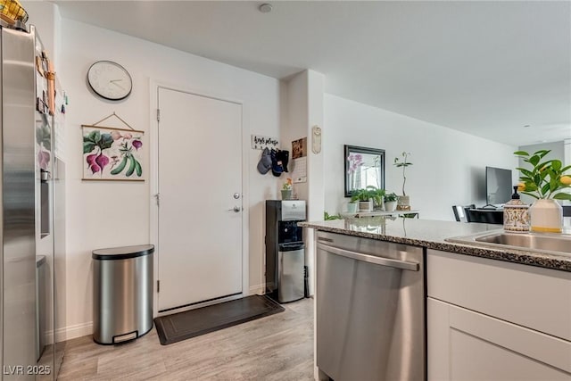 12110 Midnight Pine Rd Unit 4, Las Vegas, NV 89183 - kitchen with stainless steel dishwasher, light wood finished floors, white cabinetry, a sink, and baseboards