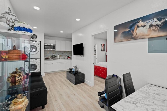 5375 Chestnut St, Las Vegas, NV 89119 - kitchen featuring stacked washer / dryer, stainless steel microwave, light wood-style floors, white cabinets, and decorative backsplash