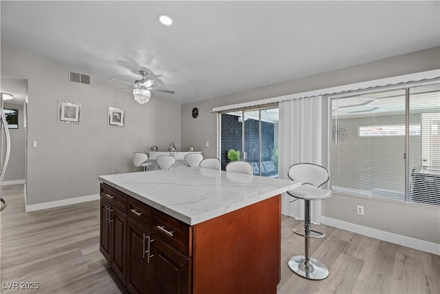 5375 Chestnut St, Las Vegas, NV 89119 - kitchen with a breakfast bar area, light wood finished floors, a ceiling fan, and a kitchen island