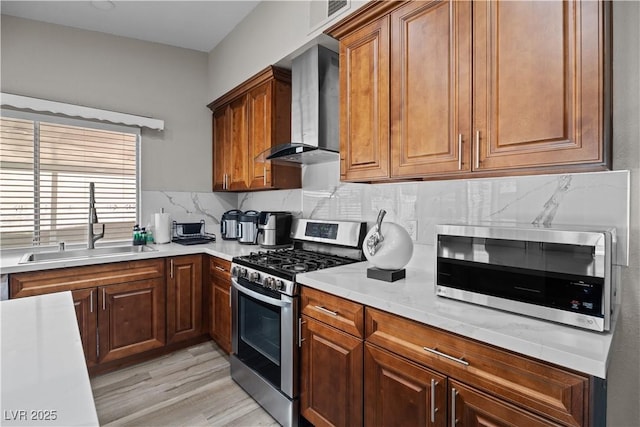 5375 Chestnut St, Las Vegas, NV 89119 - kitchen featuring appliances with stainless steel finishes, wall chimney exhaust hood, decorative backsplash, light countertops, and light wood-type flooring