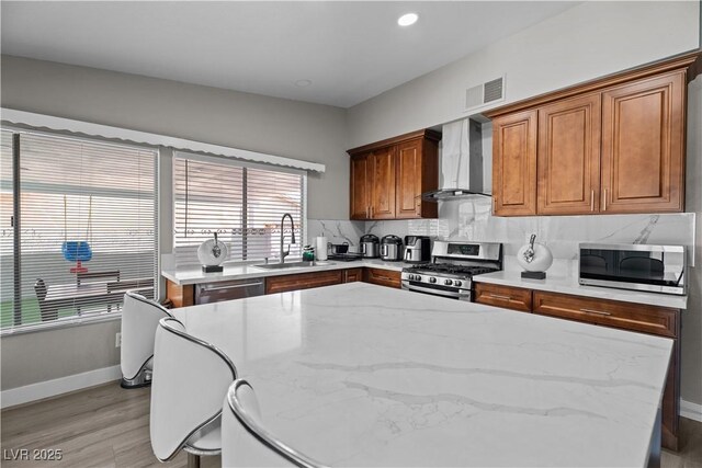 5375 Chestnut St, Las Vegas, NV 89119 - kitchen featuring wall chimney range hood, stainless steel appliances, backsplash, a center island, and light wood finished floors