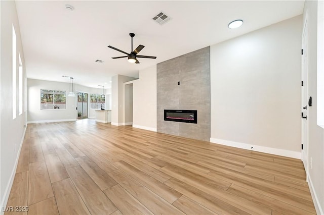 10017 Snow Crest Pl, Las Vegas, NV 89134 - unfurnished living room with ceiling fan, light wood finished floors, baseboards, and a tile fireplace