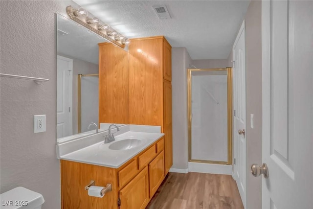 701 Capri Dr Unit 6A, Boulder City, NV 89005 - bathroom featuring vanity, a stall shower, wood finished floors, a textured wall, and a textured ceiling