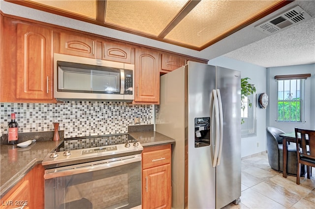 7952 Diamond Rock Way Unit 102, Las Vegas, NV 89128 - kitchen featuring stainless steel appliances, decorative backsplash, brown cabinets, and light tile patterned floors