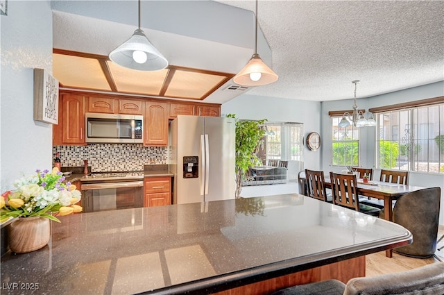 7952 Diamond Rock Way Unit 102, Las Vegas, NV 89128 - kitchen featuring appliances with stainless steel finishes, a chandelier, a peninsula, pendant lighting, and backsplash