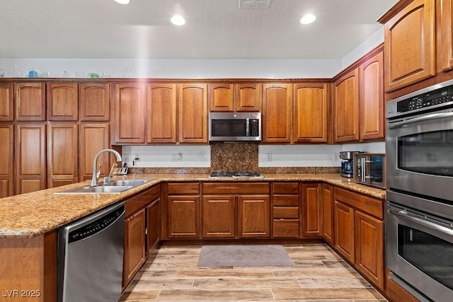 7252 Royal Melbourne Dr, Las Vegas, NV 89131 - kitchen with stainless steel appliances, a sink, brown cabinetry, light stone countertops, and recessed lighting