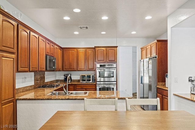 7252 Royal Melbourne Dr, Las Vegas, NV 89131 - kitchen featuring appliances with stainless steel finishes, a sink, recessed lighting, stone countertops, and brown cabinetry