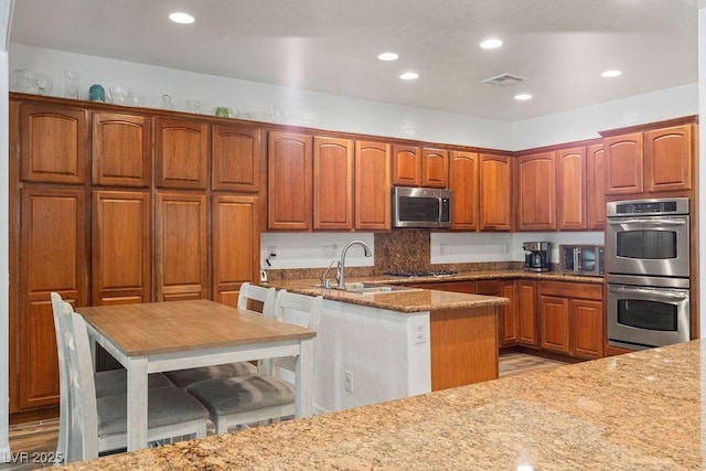 7252 Royal Melbourne Dr, Las Vegas, NV 89131 - kitchen with stainless steel appliances, a sink, recessed lighting, light stone counters, and brown cabinets