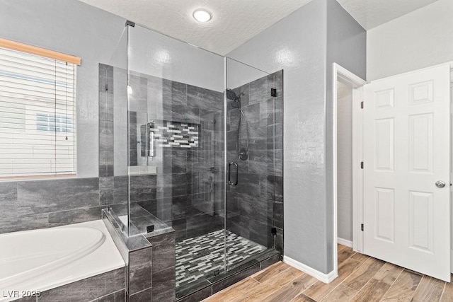 7252 Royal Melbourne Dr, Las Vegas, NV 89131 - full bathroom featuring a bath, a shower stall, wood finished floors, a textured wall, and baseboards