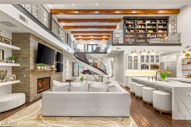 2793 Red Arrow Dr, Las Vegas, NV 89135 - living room with a towering ceiling, wood-type flooring, beamed ceiling, a large fireplace, and stairs