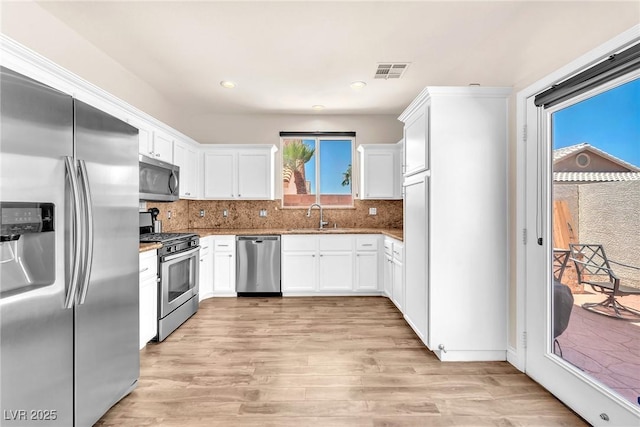 690 Great Dane Ct, Henderson, NV 89052 - kitchen with appliances with stainless steel finishes, light wood finished floors, light stone countertops, white cabinetry, and recessed lighting