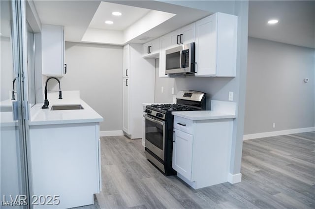 1440 Vegas Valley Dr Unit 3, Las Vegas, NV 89169 - kitchen featuring stainless steel appliances, a sink, light wood-style floors, a raised ceiling, and baseboards