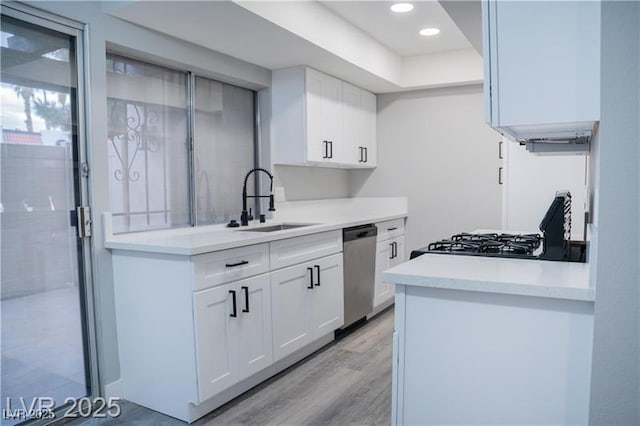 1440 Vegas Valley Dr Unit 3, Las Vegas, NV 89169 - kitchen with stainless steel dishwasher, a sink, light wood-type flooring, white cabinetry, and light countertops