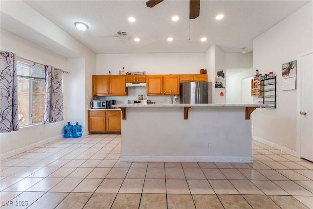 4335 Twin Peaks Dr, North Las Vegas, NV 89032 - kitchen featuring appliances with stainless steel finishes, under cabinet range hood, light countertops, brown cabinetry, and ceiling fan