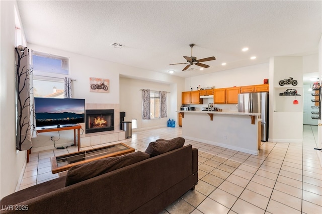 4335 Twin Peaks Dr, North Las Vegas, NV 89032 - living room featuring light tile patterned floors, a ceiling fan, recessed lighting, a tiled fireplace, and a textured ceiling