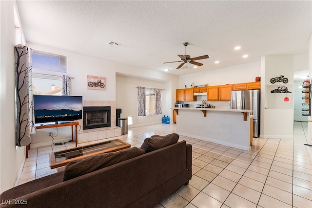 4335 Twin Peaks Dr, North Las Vegas, NV 89032 - living area with light tile patterned floors, a ceiling fan, a tiled fireplace, recessed lighting, and a textured ceiling