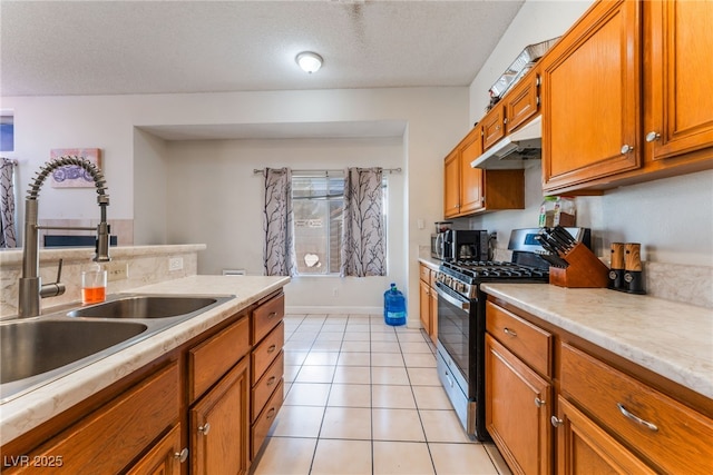 4335 Twin Peaks Dr, North Las Vegas, NV 89032 - kitchen featuring stainless steel gas range oven, under cabinet range hood, brown cabinets, light countertops, and a textured ceiling
